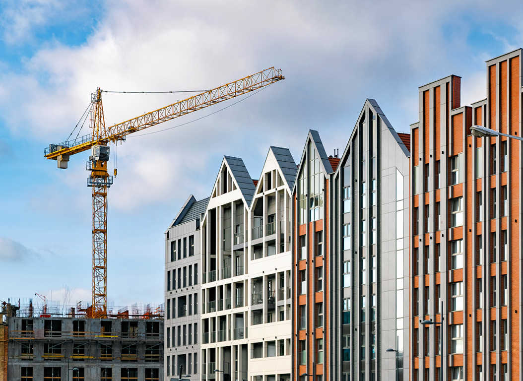 Modern block of apartments built with a brick slip façade, and another building being constructed in the background.