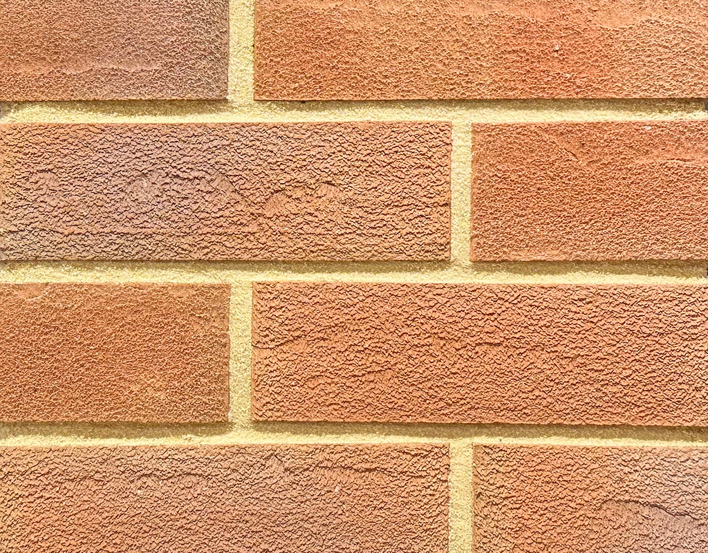 Textured red brick slips shown in a wall.